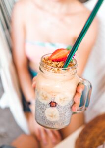 Delicious and fresh summer smoothie in a mason jar, topped with strawberries and granola.